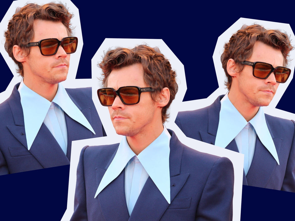 Three cutout images of Harry Styles wearing a navy blue suit with a wide light blue collar and brown-tinted square sunglasses, arranged on a dark navy background.